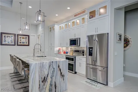 a kitchen that has a refrigerator a stove and white cabinets with wooden floor
