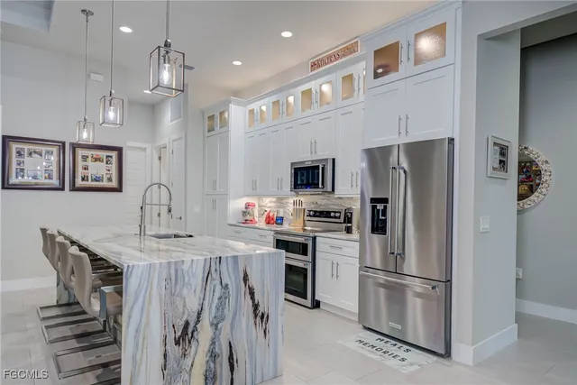 a kitchen that has a refrigerator a stove and white cabinets with wooden floor