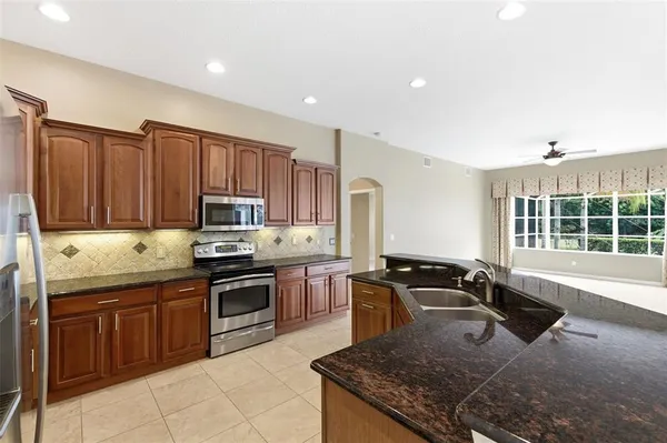 a kitchen with stainless steel appliances granite countertop a sink refrigerator and cabinets