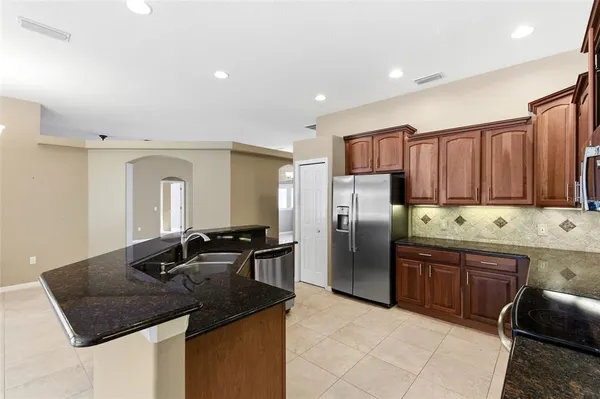a kitchen with stainless steel appliances granite countertop a refrigerator stove top oven and sink
