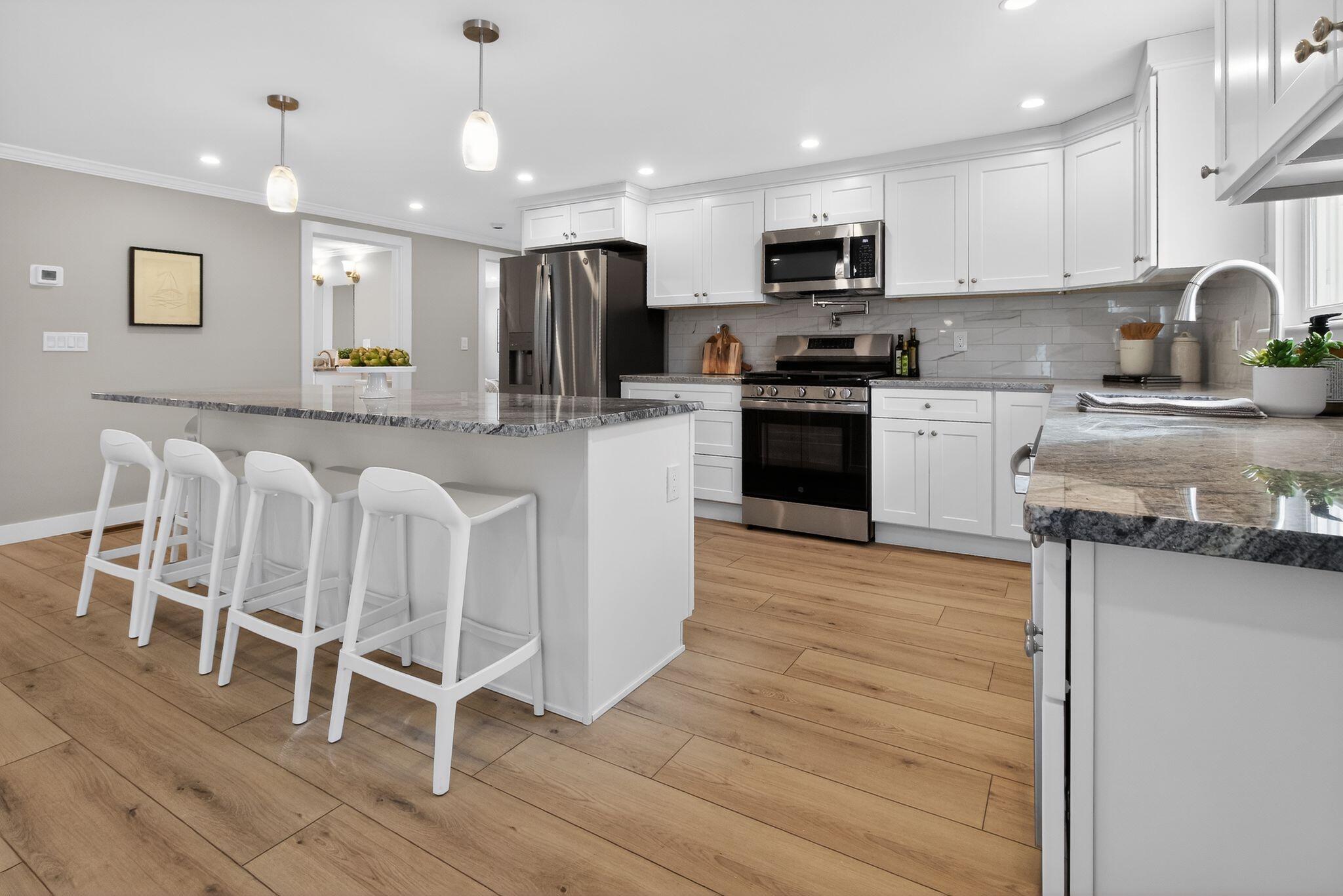 53 Eel River Road East Falmouth, MA 02536 - Photo 23 of 42 a kitchen with stainless steel appliances granite countertop a stove top oven a sink a refrigerator with grey cabinets and wooden floor