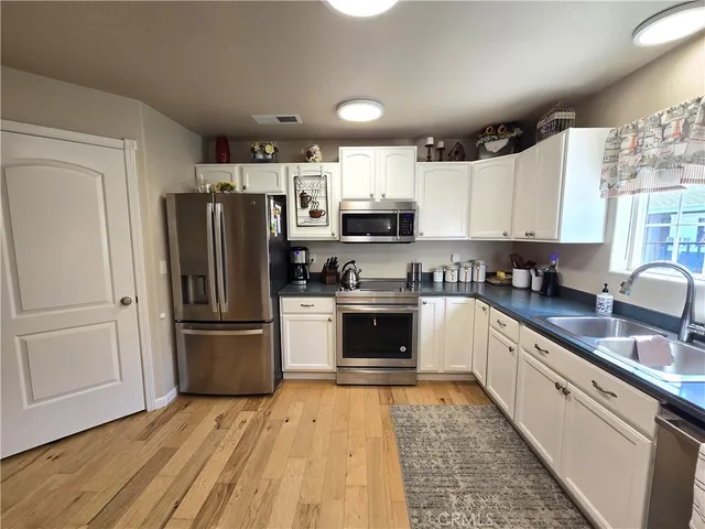 a kitchen with granite countertop a refrigerator stove and sink with wooden floor