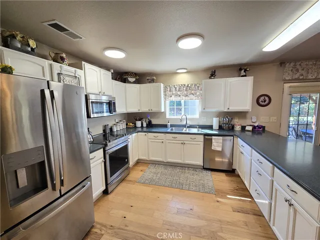 a large kitchen with stainless steel appliances kitchen island granite countertop a refrigerator a sink a stove a microwave and island