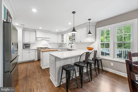 a dining room with stainless steel appliances kitchen island granite countertop a stove a refrigerator a oven with a dining table and chairs with wooden floor