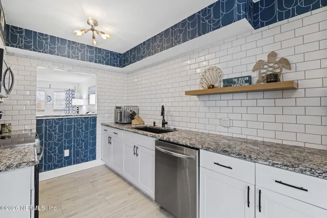 a kitchen with granite countertop stainless steel appliances a sink stove and refrigerator