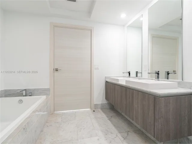 a bathroom with a double vanity sink mirror and bathtub