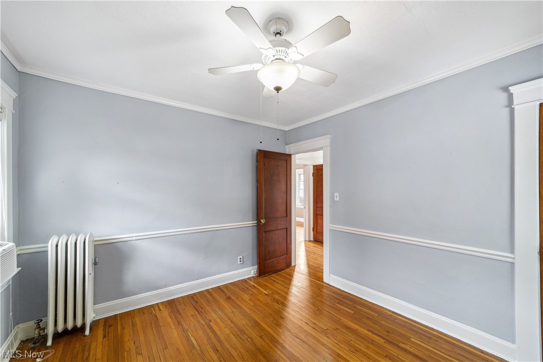 3045 East Overlook Road Cleveland, OH 44118 - Photo 21 of 29 Bedroom featuring crown molding, wood-type flooring, radiator heating unit, and ceiling fan
