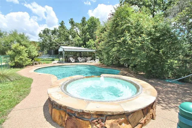 a view of a patio with a dining table and chairs under an umbrella with a small yard