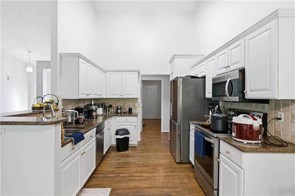 3324 Dunbar Lane Suwanee, GA 30024 - Photo 11 of 42 a kitchen with stainless steel appliances granite countertop a refrigerator a stove top oven a sink dishwasher and white cabinets