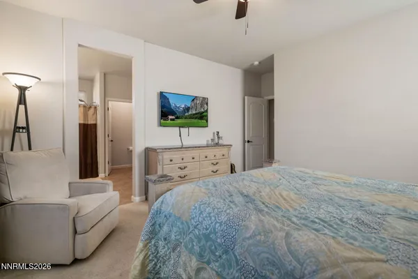 a bedroom with a bed a couch and a flat tv screen on a dresser