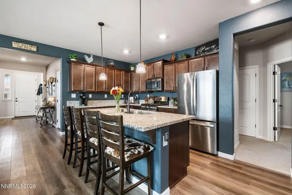 a kitchen with stainless steel appliances a refrigerator a stove a sink and a dining table with wooden floor