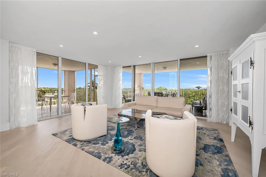 a living room with furniture a large window and wooden floor