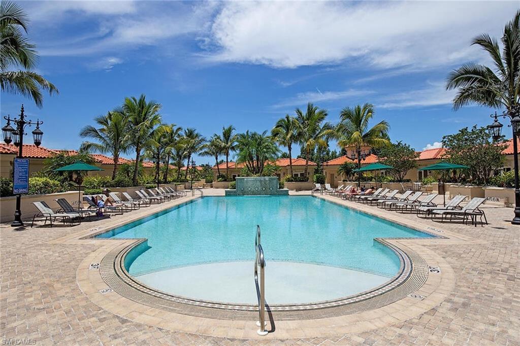 6597 Nicholas Boulevard, Unit 401 Naples, FL 34108 - Photo 22 of 28 a view of a swimming pool with a lawn chairs under an umbrella
