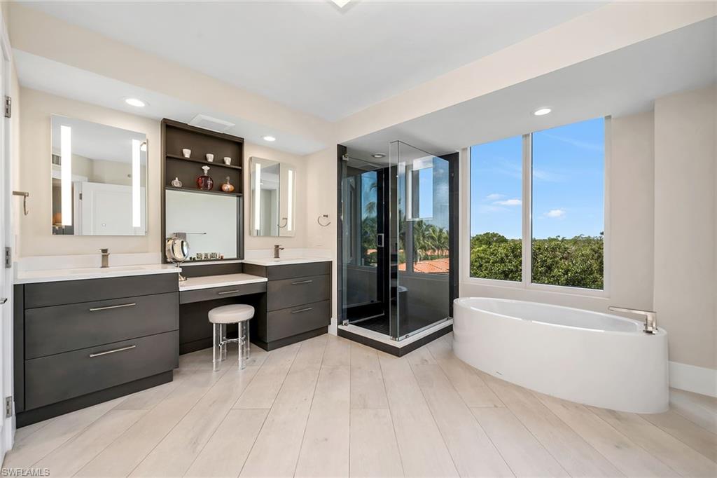6597 Nicholas Boulevard, Unit 401 Naples, FL 34108 - Photo 9 of 28 a spacious bathroom with a tub sink and mirror