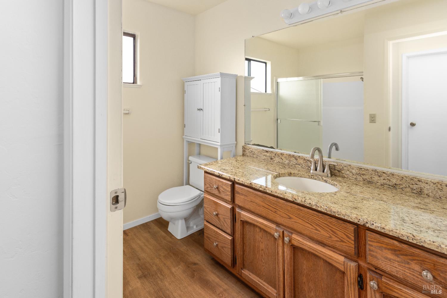 424 B Mason Street Healdsburg, CA 95448 - Photo 24 of 27 a bathroom with a granite countertop toilet a sink and a mirror