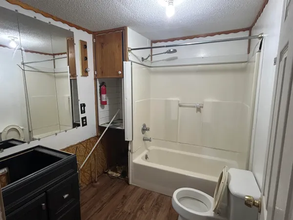 a bathroom with a granite countertop bathtub shower sink vanity and toilet
