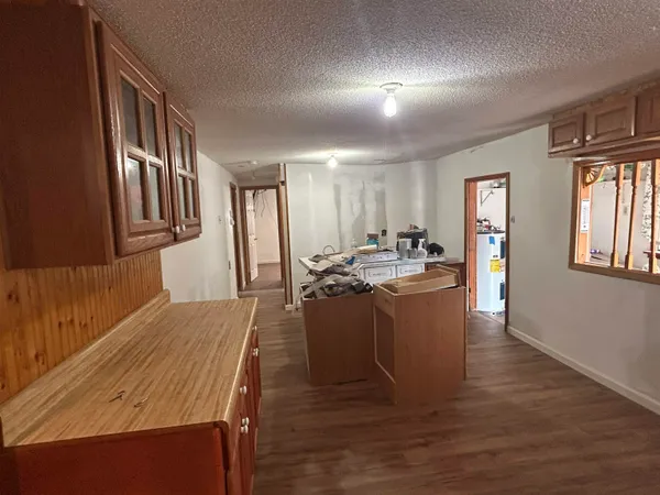 a living room with stainless steel appliances kitchen island granite countertop a refrigerator a stove a sink dishwasher and wooden cabinets with wooden floor
