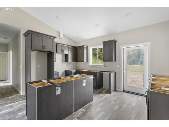 a kitchen with stainless steel appliances granite countertop a refrigerator a sink dishwasher a stove and a dining table with wooden floor