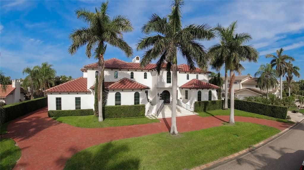 a view of a white house with a big yard and palm trees