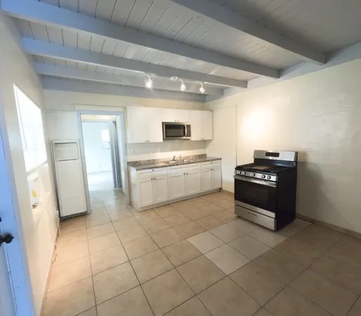 a kitchen with granite countertop a refrigerator and a stove top oven