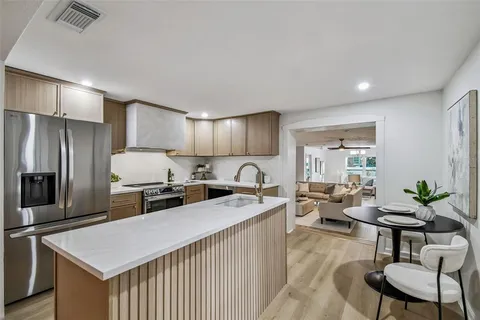 a kitchen with stainless steel appliances granite countertop a refrigerator a stove a sink a dining table and chairs with wooden floor