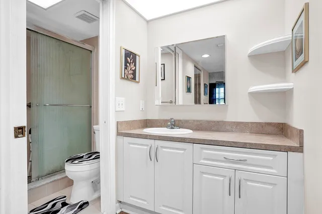 a bathroom with a granite countertop sink a toilet and a mirror