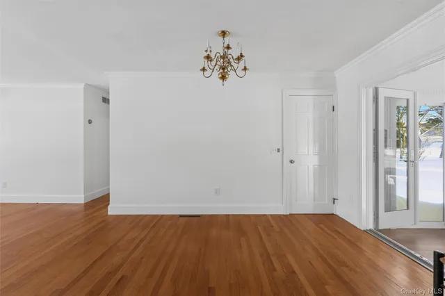 an empty room with wooden floor and a chandelier