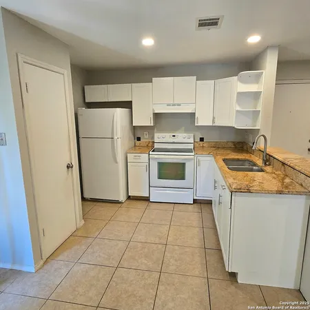 a kitchen with a sink a stove a refrigerator and a cabinets