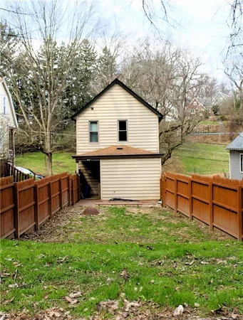 a view of a backyard with wooden fence and a bench