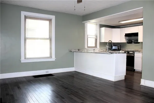 a kitchen with granite countertop wooden floors and white cabinets