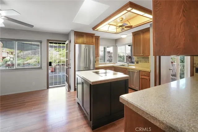 a kitchen with a stove a sink dishwasher and a refrigerator with wooden floor
