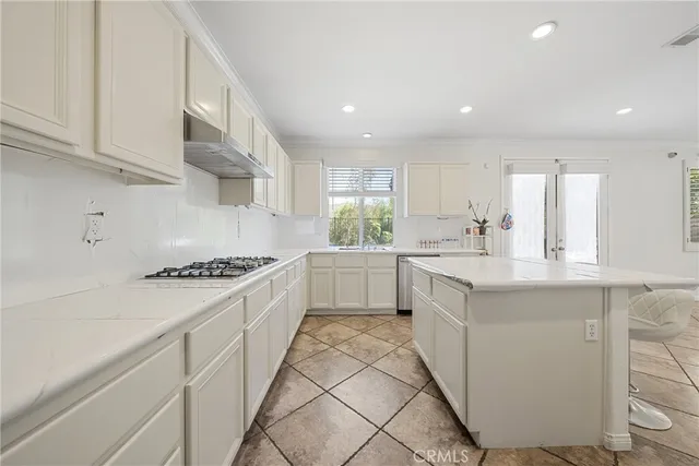 a kitchen with granite countertop a sink stove a refrigerator and white cabinets with wooden floor