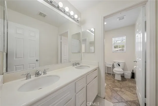 a spacious bathroom with a double vanity sink mirror and toilet
