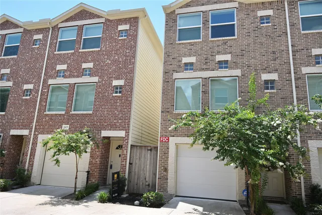 a view of a brick house with a tree and plants