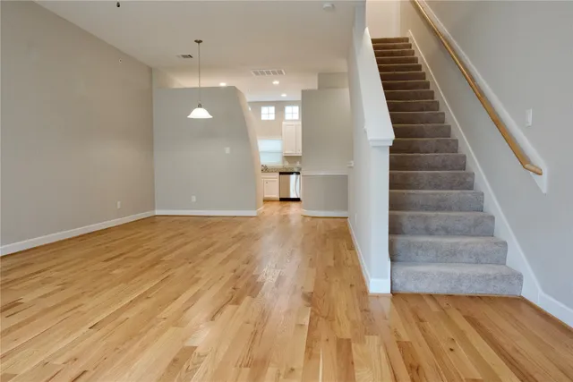 a view of an empty room with wooden floor and stairs