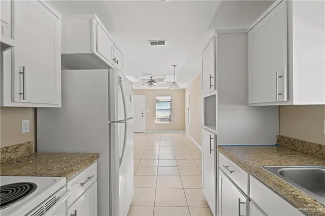 a kitchen with granite countertop a sink stove and refrigerator