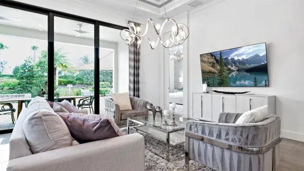 a living room with furniture a large window and a chandelier