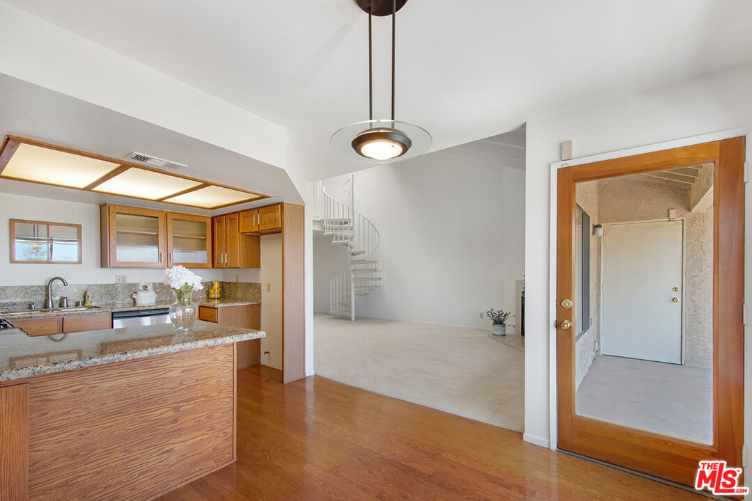 4451 Don Ricardo Drive, Unit 9 Los Angeles, CA 90008 - Photo 5 of 23 a kitchen with stainless steel appliances granite countertop a sink and a wooden floor