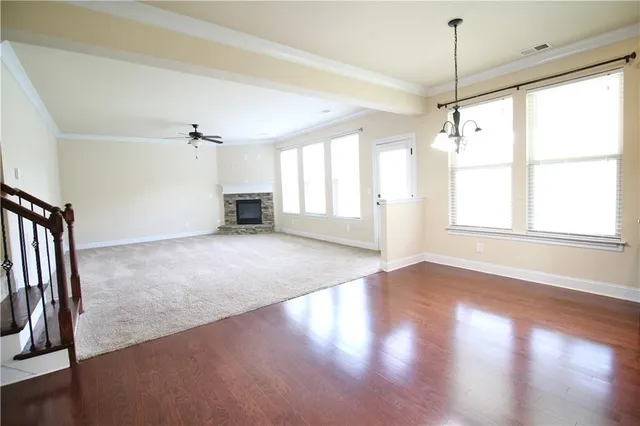 an empty room with wooden floor fan and windows
