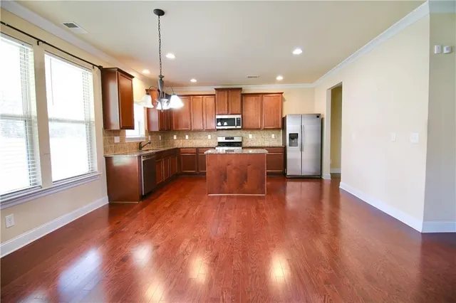 a kitchen with stainless steel appliances granite countertop wooden floors a stove and a refrigerator