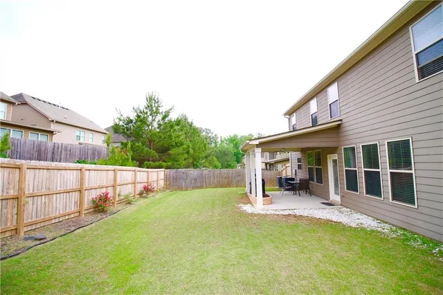 a view of a backyard with a barbeque grill and wooden fence
