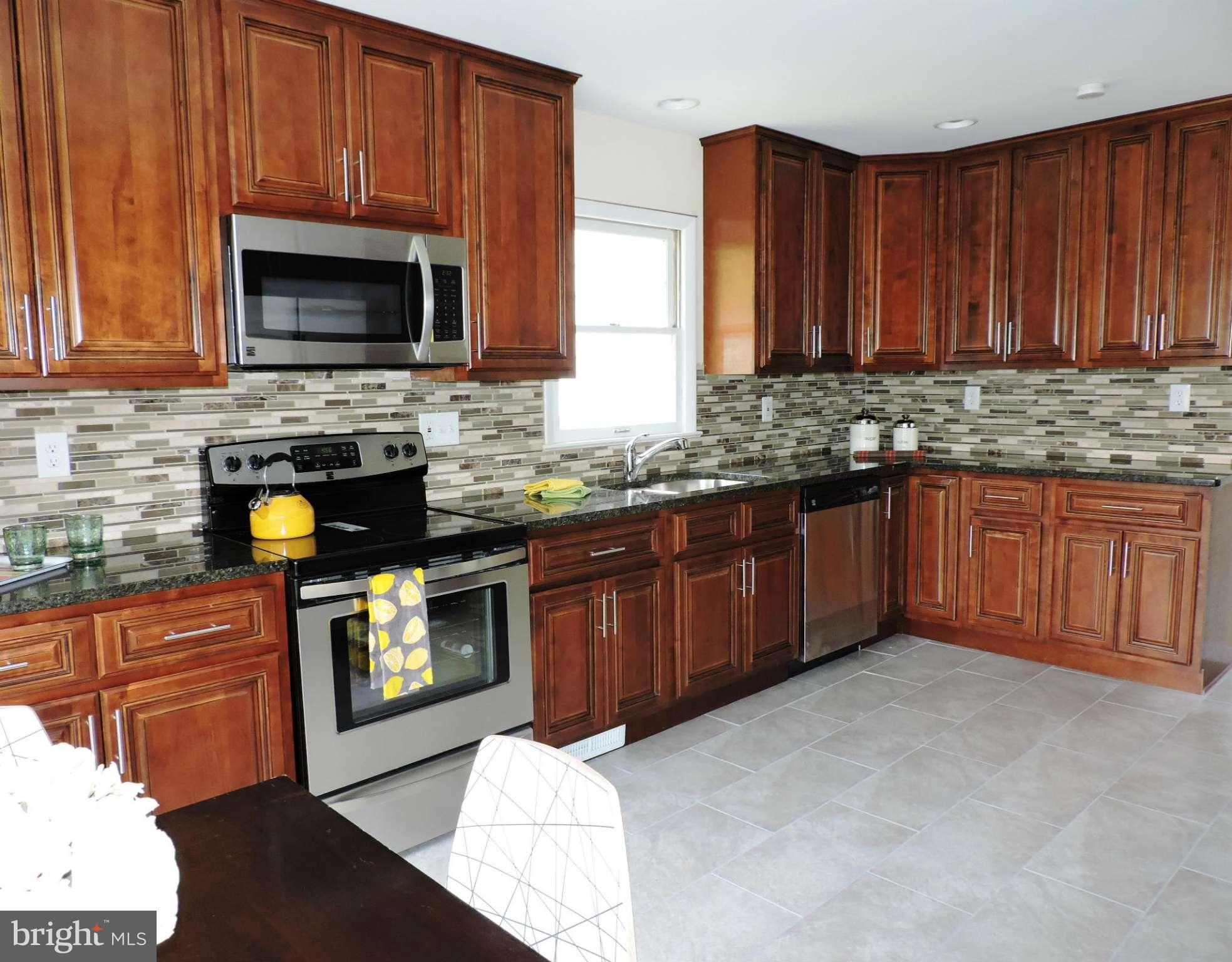 5011 Roslyn Road Annandale, VA 22003 - Photo 7 of 28 a kitchen with stainless steel appliances granite countertop wooden cabinets a stove top oven a sink and dishwasher