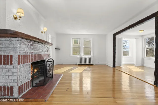 a view of an empty room with fire place and windows
