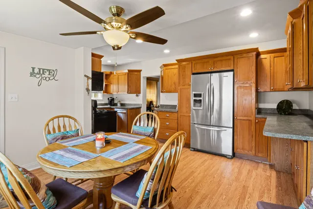 a kitchen with stainless steel appliances granite countertop a dining table chairs refrigerator and sink