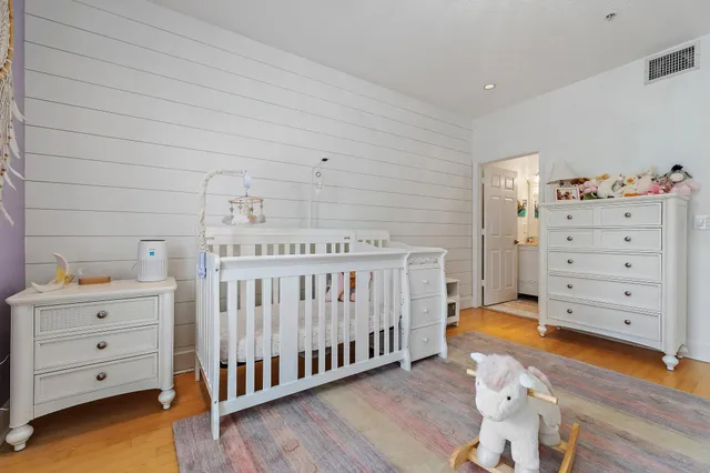 a view of a bedroom with baby crib and wooden floor