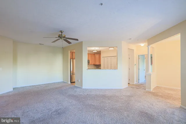 an empty room with windows and refrigerator
