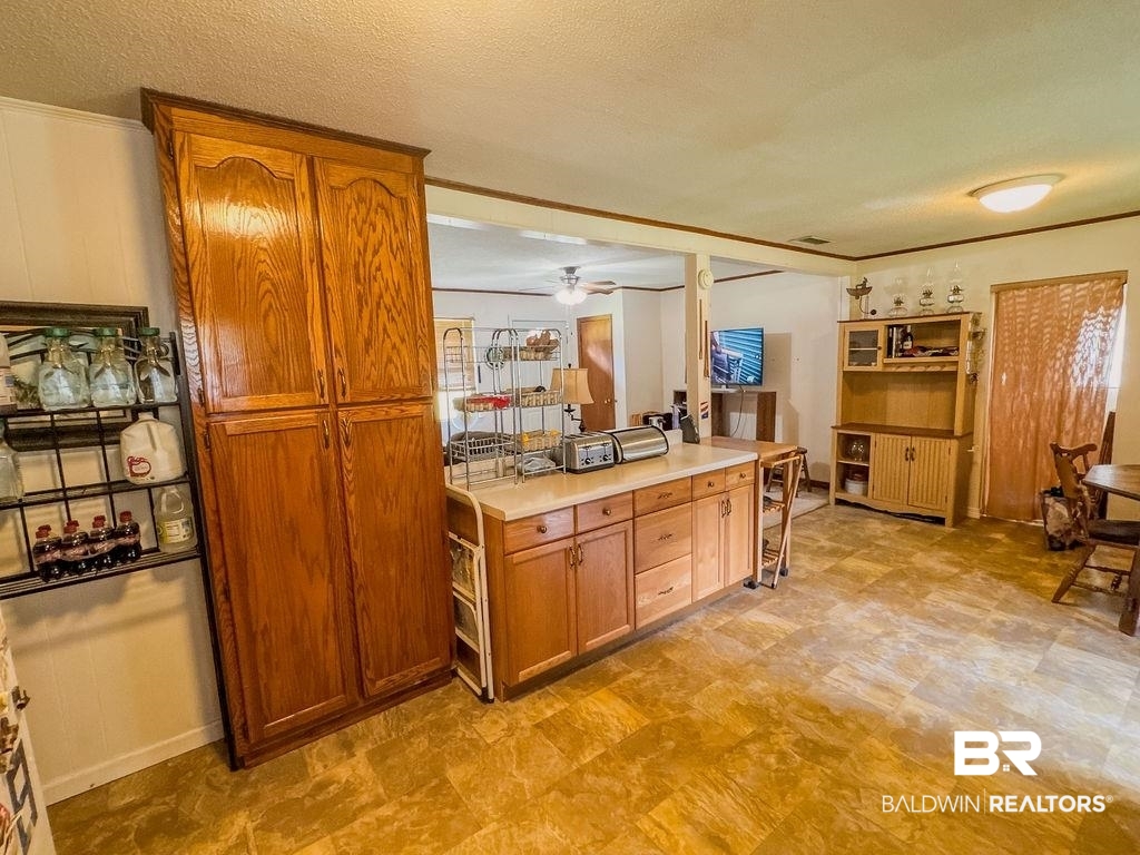 1456 Allen Walker Road Grove Hill, AL 36451 - Photo 15 of 28 Kitchen featuring a textured ceiling, brown cabinets, light countertops, and a ceiling fan