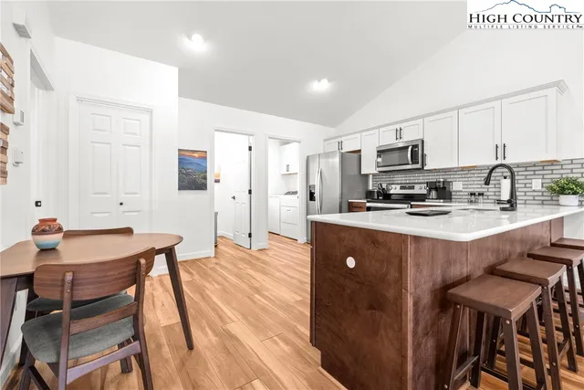 a kitchen with kitchen island granite countertop a sink a stove a refrigerator cabinets and chairs