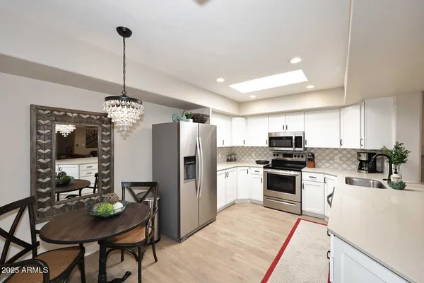 a kitchen with stainless steel appliances kitchen island granite countertop a table chairs refrigerator and microwave