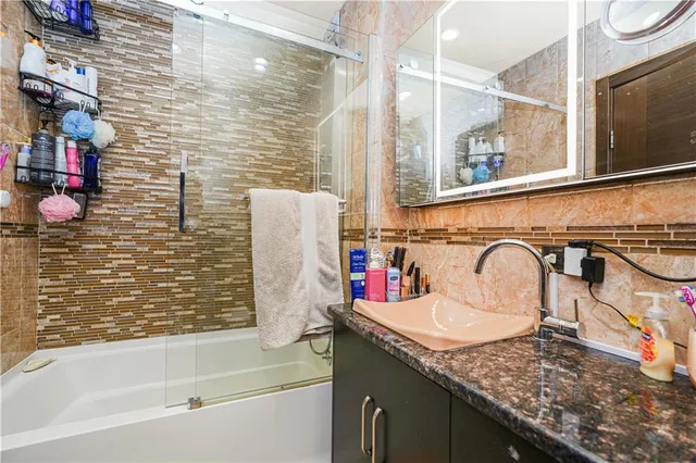 a bathroom with a granite countertop sink a mirror and shower